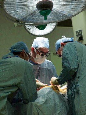 Three male surgeons operating on a patient.