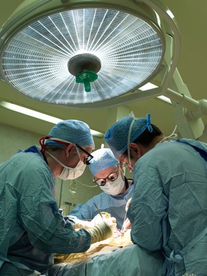 view Three male surgeons operating on a patient.