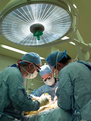 Three male surgeons operating on a patient.