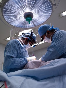 Two male surgeons operating on a patient.