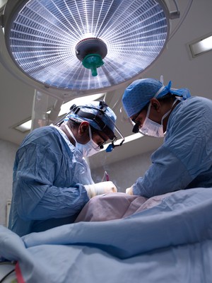 view Two male surgeons operating on a patient.