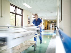 view ODP moving a hospital trolley bed down a corridor, UK.