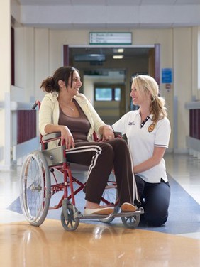 Physiotherapist with patient in hospital corridor, UK.