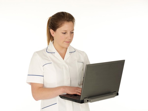 Young white female health professional in uniform with laptop