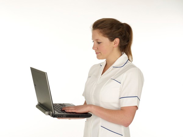 Young white female health professional in uniform with laptop