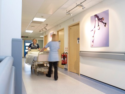 Two nurses transporting a bed down a hospital corridor