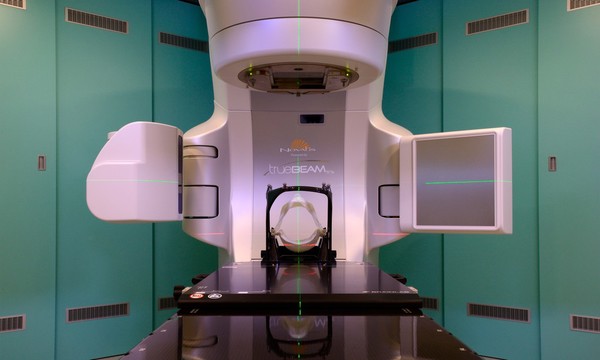 Linear accelerator (LINAC) with thermoplastic mask. The mask is used for immobilisation for stereotactic radiosurgery to treat brain tumours.