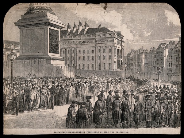 Chelsea Pensioners in a procession in Trafalgar Square, heading towards the Strand, to the left the base of the Nelson Column, fenced-off. Wood engraving.