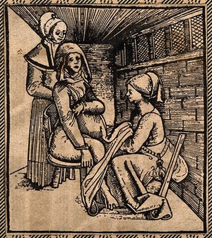 view A woman seated on a obstetrical chair giving birth aided by a midwife who works beneath her skirts. Woodcut.