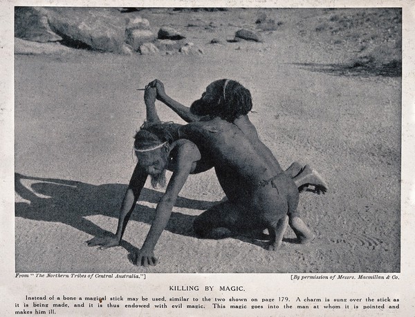 Two Australian aborigines performing a ceremony with a magical stick to make another person ill. Halftone.