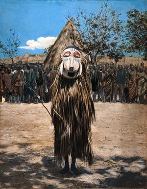view An African shaman or medicine man dressed in ritual mask and costume. Coloured photograph.