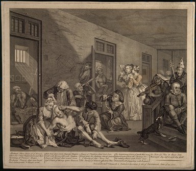 An insane man (Tom Rakewell) sits on the floor manically grasping at his head, his lover (Sarah Young) cries at the spectacle while two attendants attach chains to his legs; they are surrounded by other lunatics at Bethlem hospital, London. Engraving by W. Hogarth after himself, 1735.