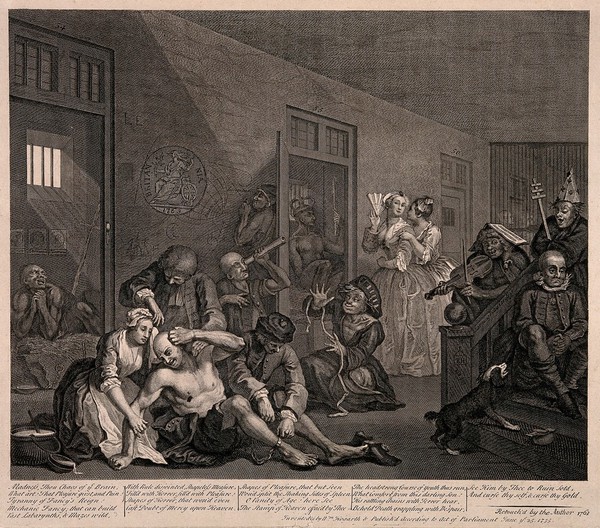 An insane man (Tom Rakewell) sits on the floor manically grasping at his head, his lover (Sarah Young) cries at the spectacle while two attendants attach chains to his legs; they are surrounded by other lunatics at Bethlem hospital, London. Engraving by W. Hogarth, 1763.