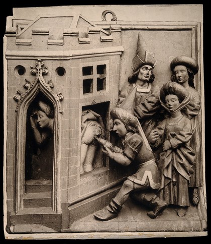 A physician administering a clyster to an embarrassed woman who hides her self and presents her behind through a window, female friends observe the scene. Photograph after a stone bas-relief in Bruges archaeological museum.