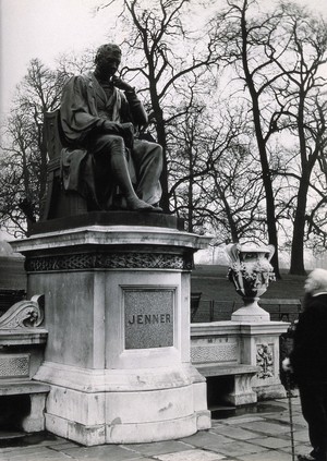 view W. Calder Marshall's statue of Edward Jenner in Kensington Gardens, London; an old man standing in front of it. Photograph, 1920/1940 (?).