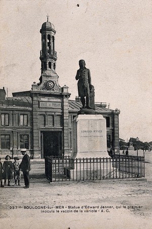 view Statue of Edward Jenner in Boulogne-sur-Mer, in front of the halle au poisson; man and children next to it. Postcard, 1920/1940.