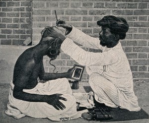 view An amateur barber dressing a man's hair in a street. Process print.