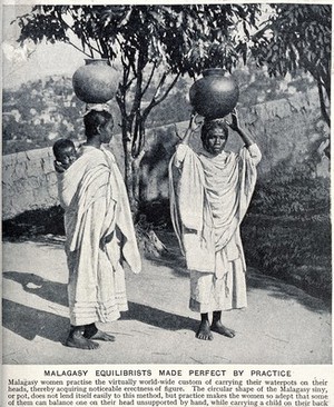 view Two Malagasy women carrying waterpots on their heads; the woman on the left also carries a child on her back. Halftone.