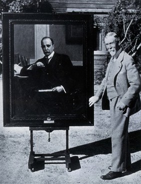 Seymour Thomas standing next to his portrait of Sir William Osler. Photograph.