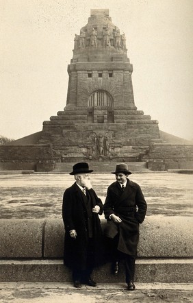 Georg Sticker and an unknown companion, in front of a war memorial (?). Photograph.