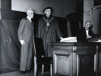 A.T. Glenny receiving the Jenner medal from Sir Francis Walshe, with Austin Bradford Hill. Photograph, 1953.