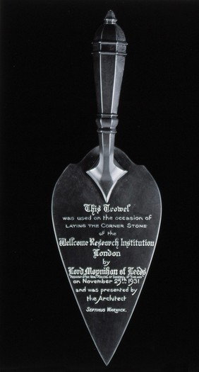The silver trowel used by Henry S. Wellcome to lay the corner-stone of the Wellcome Building in 1931. Photograph.