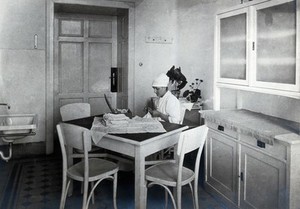 view University Children's Hospital, Vienna: a nurse sewing an embroidered cloth. Photograph, 1921.