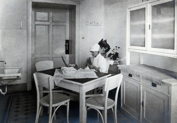 University Children's Hospital, Vienna: a nurse sewing an embroidered cloth. Photograph, 1921.