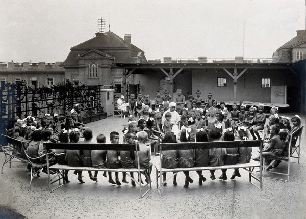 University Children's Hospital, Vienna: children in the roof garden being read to by a nurse. Photograph, 1921.