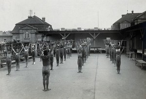 view University Children's Hospital, Vienna: children exercising with wooden batons, on the roof garden. Photograph, 1921.