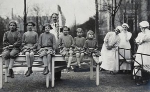 view University Children's Hospital, Vienna: a row of girl patients, outdoors, being measured for height. Photograph, 1921.