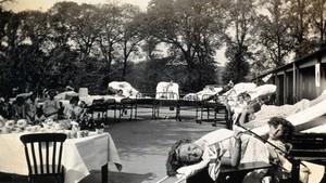 view St Nicholas' and St Martin's Orthopaedic Hospital, Pyrford, Surrey: a girl on her back on a bed at an outdoor party. Photograph, c. 1935.