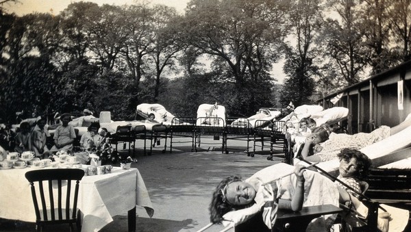 St Nicholas' and St Martin's Orthopaedic Hospital, Pyrford, Surrey: a girl on her back on a bed at an outdoor party. Photograph, c. 1935.