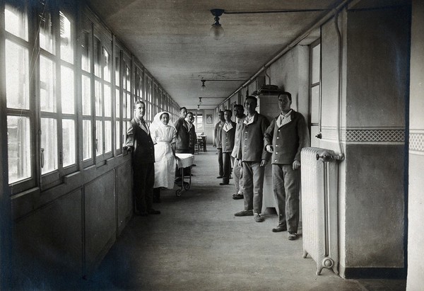 British Red Cross Hospital, Turin: patients and nurses standing in a corridor. Photograph, c. 1918.