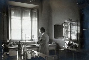 view British Red Cross Hospital, Turin: man wearing Red Cross arm band working in the pharmacy. Photograph, c. 1918.