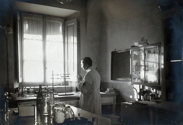 British Red Cross Hospital, Turin: man wearing Red Cross arm band working in the pharmacy. Photograph, c. 1918.