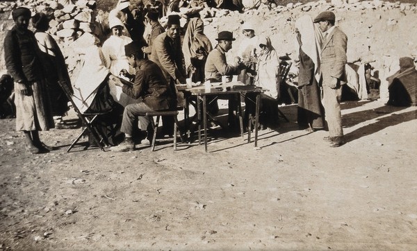 Smallpox epidemic, Palestine: group of people from a camp being vaccinated. Photograph, 1922.