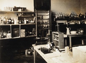 view Military Hospital V.R. 76, Ris-Orangis, France: room with bottles, measuring scales and weights, possibly the pharmacy. Photograph, 1916.