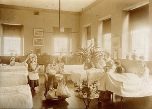 view The Royal United Hospital, Bath: nurses and patients on a girls' ward. Photograph, ca. 1870.