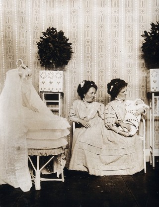 Josefa Blažek and Rosalia Blažek (Rosa Blažek), female conjoined twins, seated, holding Franzl, the baby of Rosa. Photograph, ca. 1910.