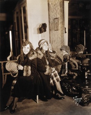 view Daisy and Violet Hilton, conjoined twins, trying on hats in a hat shop. Photograph, c. 1927.