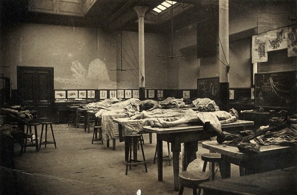 The interior of a dissecting room in Edinburgh, with half-covered cadavers on benches. Photograph, 1889.