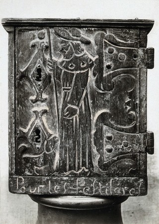 A wooden collection box for the benefit of plague victims, carved in low relief with the figure of Saint Roch as a pilgrim. Photograph.