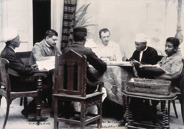 A group of men taking notes at a table, during a plague epidemic in Mandalay. Photograph, 1906.