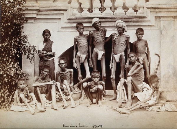 Famine in India: emaciated young men wearing loin cloths and a woman wearing a sari. Photograph attributed to Willoughby Wallace Hooper, 1876/1878.