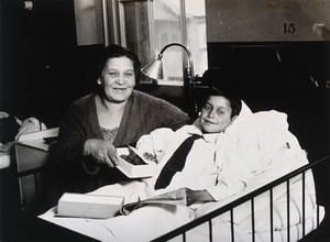 view A mother visiting her son in a hospital bed following his operation during which she gave a pint of her own blood. Photograph, 1925.