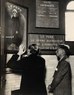 view Temple of the Antoinistes, Liège: the priest faces a portrait of Father Antoine, entreating him to help heal a sick follower. Photograph by Kurt Lubinski, 1920/1940.