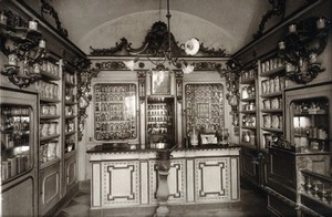 view The ornate sixteenth-century pharmacy of S. Maria della Scala, Sorrento: interior with decorated bench and a large mortar in centre. Photograph.