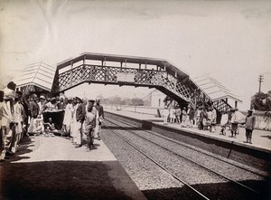 view Two groups of people on opposite sides of a railway line in Bombay awaiting the arrival of a plague patient by train. Photograph, 1896/1897.