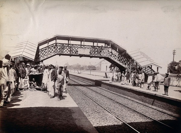 Two groups of people on opposite sides of a railway line in Bombay awaiting the arrival of a plague patient by train. Photograph, 1896/1897.